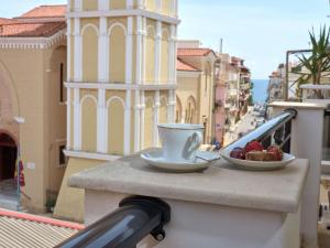 a cup of coffee and a bowl of fruit on a balcony at Giovanna's Lux Apartment in Zakynthos