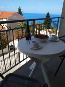 a table with a glass of wine and a bowl of fruit on a balcony at Sunny Blue apartments in Omiš