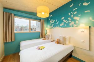 2 Betten in einem Zimmer mit blauen Wänden in der Unterkunft Center Parcs Villages Nature Paris in Bailly-Romainvilliers