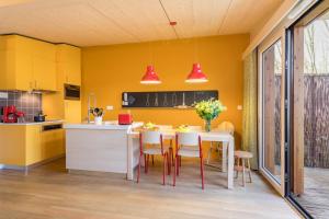 a kitchen with yellow walls and a white table and chairs at Center Parcs Villages Nature Paris in Bailly-Romainvilliers
