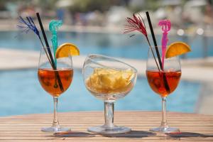 three wine glasses sitting on a wooden table at Fantinello Hotel in Caorle