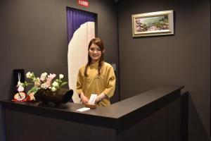 a woman standing at a counter with a surfboard at Stay SAKURA Kyoto Nijo Seasons in Kyoto
