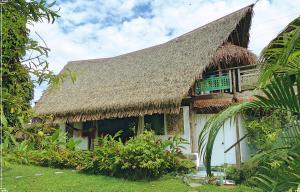 uma casa com telhado de palha e relva em Island Home em Uturoa