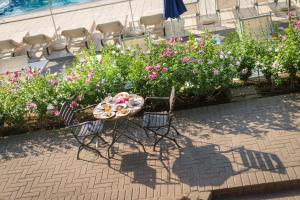 a table with a plate of food on it next to flowers at Fantinello Hotel in Caorle