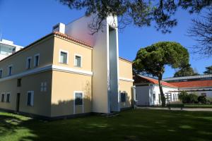 un bâtiment avec un arbre dans la cour dans l'établissement INATEL Caparica, à Costa da Caparica