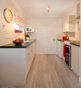 a kitchen with white cabinets and a bowl of fruit on the counter at 33 The Fairway in Newton Ferrers