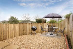 a backyard with a grill and a table with an umbrella at 33 The Fairway in Newton Ferrers