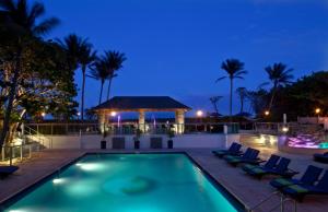 a swimming pool at night with chairs and a gazebo at Jupiter Beach Resort & Spa in Jupiter