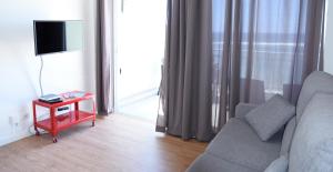 uma sala de estar com um sofá, uma televisão e uma mesa em Apartamento Primera Línea Playa de Las Canteras em Las Palmas de Gran Canaria