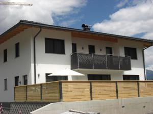 biały budynek z drewnianym płotem przed nim w obiekcie die Gartenwohnung - Tanja Tipotsch w mieście Schwendau