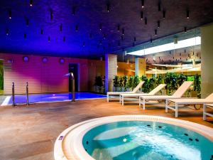 a pool in a building with lounge chairs and a spa at Golden Tulip Międzyzdroje Residence in Międzyzdroje