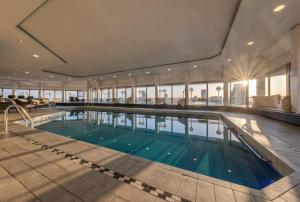 a large swimming pool in a building with windows at Clayton Hotel Düsseldorf City Centre in Düsseldorf