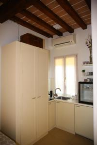 kuchnia z białymi szafkami, umywalką i oknem w obiekcie Masone Home w mieście Modena