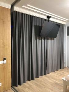 ein schwarzer Vorhang in einem Zimmer mit einem TV in der Unterkunft LUX Apartment Ruska in Lwiw