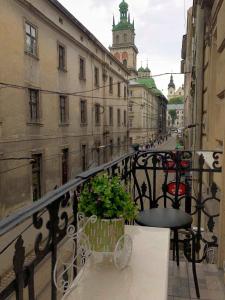 einen Balkon mit einem Stuhl und einer Pflanze auf einer Stadtstraße in der Unterkunft LUX Apartment Ruska in Lwiw