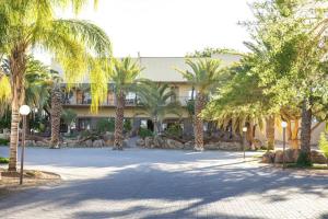 a large building with palm trees in front of it at Augrabies Falls Lodge & Camp in Augrabies
