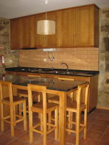 a kitchen with wooden cabinets and a island with bar stools at Ares do Montemuro in Campo Benfeito