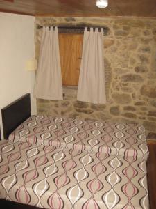 a bedroom with a bed and a stone wall at Ares do Montemuro in Campo Benfeito
