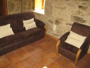 a living room with a brown couch and a chair at Ares do Montemuro in Campo Benfeito