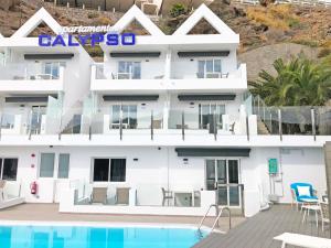 een groot wit gebouw met een zwembad ervoor bij Calypso Boutique Apartments in Puerto Rico de Gran Canaria