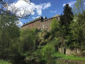 a building on top of a hill next to a river at Alte Rentei in Schleiden