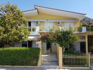 una casa amarilla con una valla y árboles en Villa "Eva" - Entire beachfront holiday home - 4S, en Aghia Marina