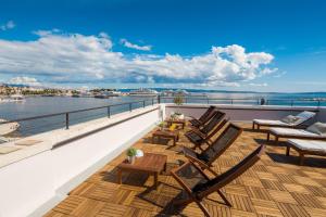 a balcony with wooden tables and chairs and the water at Belvedere Luxury Rooms - Breathtaking View in Split