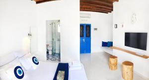 Habitación blanca con puerta azul y TV. en Loukia Studios & Suites, en Kini