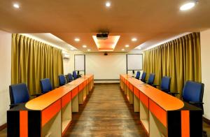 uma sala de conferências com cadeiras azuis e um ecrã em Pleasant Boulevard MG road em Bangalore