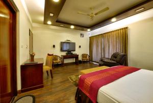 um quarto de hotel com uma cama e uma televisão em Pleasant Boulevard MG road em Bangalore