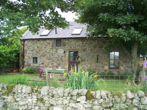 a stone house with a stone fence in front of it at Charming cottage with loch and hill views nr Edinburgh in Cobbinshaw