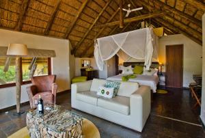 a bedroom with a bed and a couch in a room at Tau Game Lodge in Madikwe Game Reserve