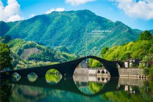 un ponte sull'acqua con montagne sullo sfondo di Le Casine del Borgo a Borgo a Mozzano