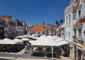 a street with tables and umbrellas in a town at Cascais Holiday House - Checkinhome in Cascais