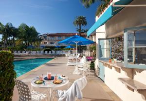 a patio with a table and chairs next to a pool at Harbor View Inn in Santa Barbara