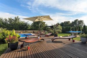 a deck with benches and an umbrella and a pool at Villa NaNa - modern Villa with a pool surrounded by nature, Istria-Pula in Valtura