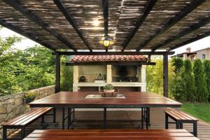 un patio con pérgola de madera, mesa y bancos en Villa NaNa - modern Villa with a pool surrounded by nature, Istria-Pula, en Valtura