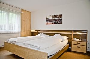 ein Schlafzimmer mit einem großen Bett mit weißer Bettwäsche in der Unterkunft Apartment Schönegg - GRIWA RENT AG in Grindelwald