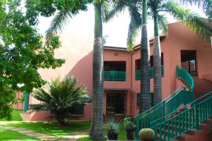 a pink house with palm trees in front of it at River Bird Guest House in Lusaka