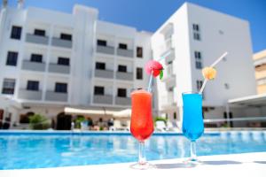 three cocktails sitting on a table near a swimming pool at Apartamentos Marian in San Antonio