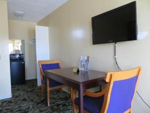 Habitación con mesa, sillas y TV en la pared. en Aqua Venture Inn, en Long Beach