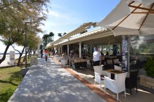 a restaurant with white chairs and tables and umbrellas at Apartmani Dekovic Materada in Poreč