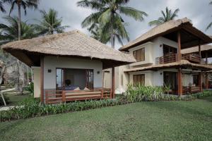 a house with a thatched roof and a yard at Qunci Villas Resort in Senggigi