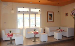 una stanza con sedie e tavoli bianchi e una finestra di Hotel Eraclea a Lido di Jesolo