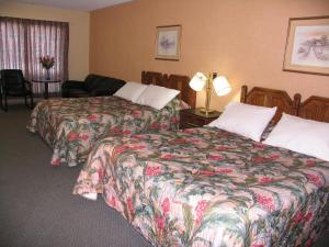 a hotel room with two beds and a chair at Seven Oakes Motel in Kingston