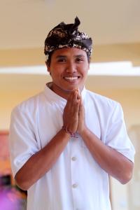 un hombre está sonriendo mientras se agarra las manos en Bali Seascape Beach Club en Candidasa