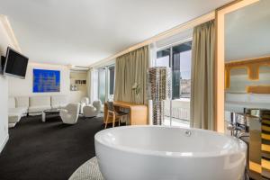 a bathroom with a tub and a living room at Room Mate Oscar, Madrid in Madrid