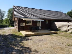 a small cabin with a deck with a table and chairs at Jagthytten in Randbøldal