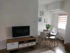 a living room with a tv and a table with chairs at Apartments Porat in Tivat