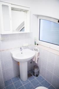 ein weißes Bad mit einem Waschbecken und einem Fenster in der Unterkunft Apartment Dove with sea view and free parking in Dubrovnik
